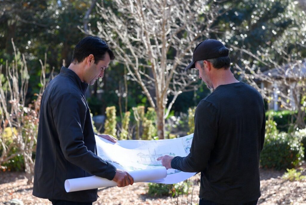 Homeowner and landscape designer reviewing a landscape plan outdoors in a winter garden